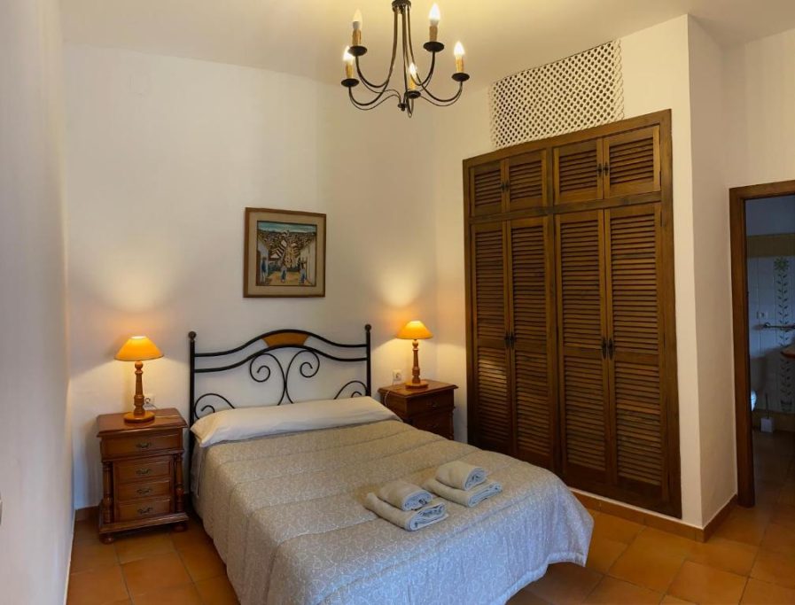 Dormitorio acogedor con cama doble, mesitas de noche y armario de madera.